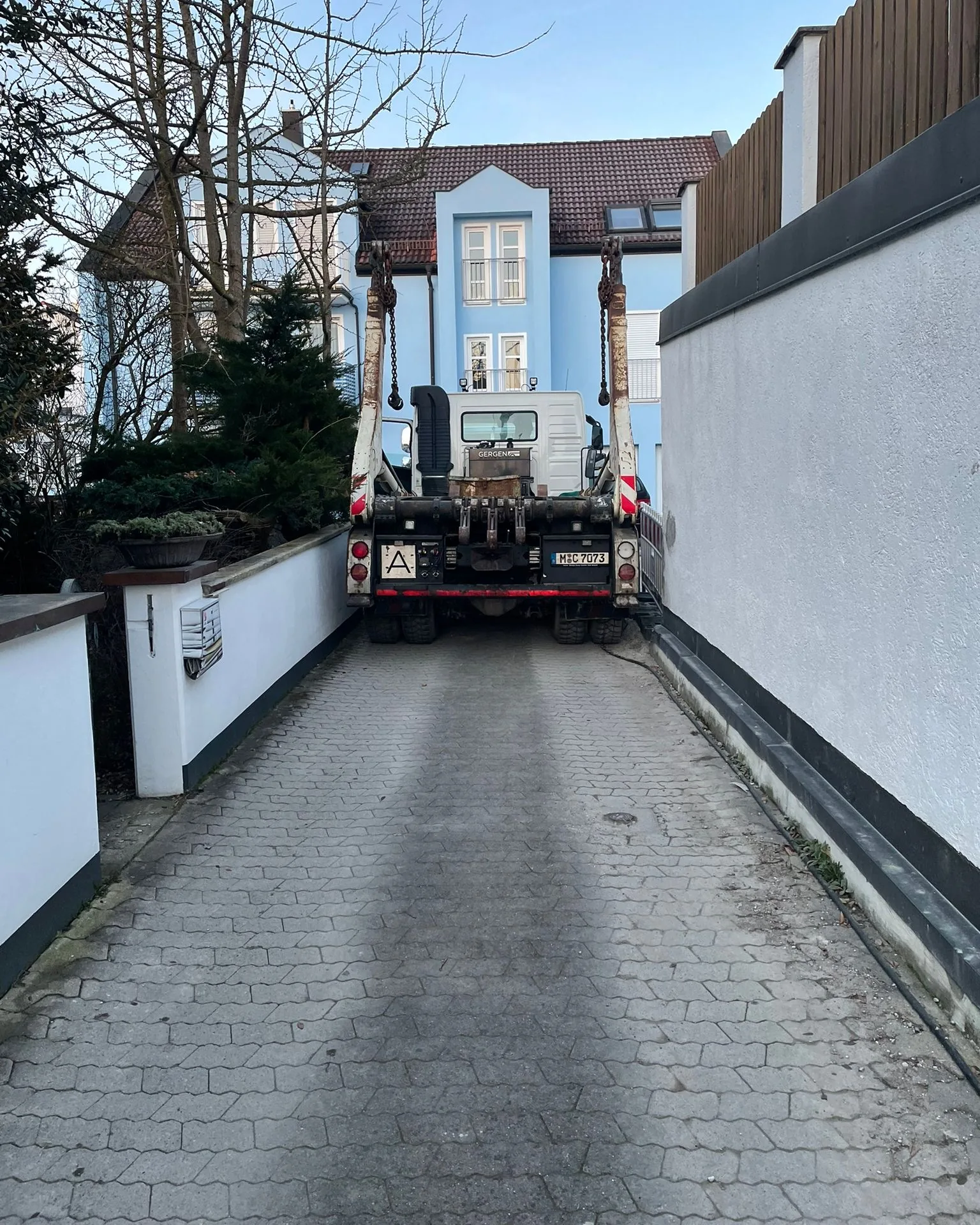 Absetzkipper von Contra Müll setzt einen Absetzcontainer in einer engen Einfahrt ab
