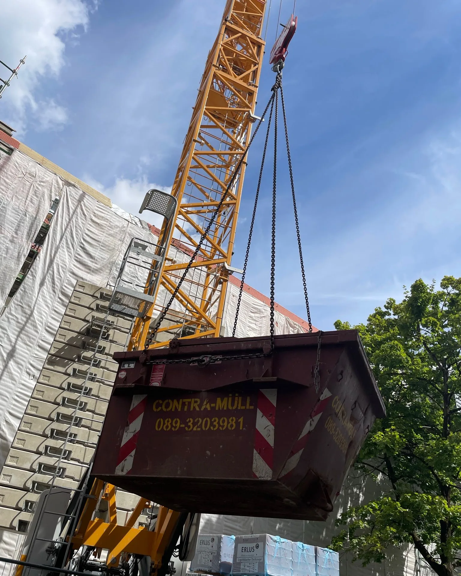 Kranbarer Container von Contra Müll hängt am Baukran einer Baustelle